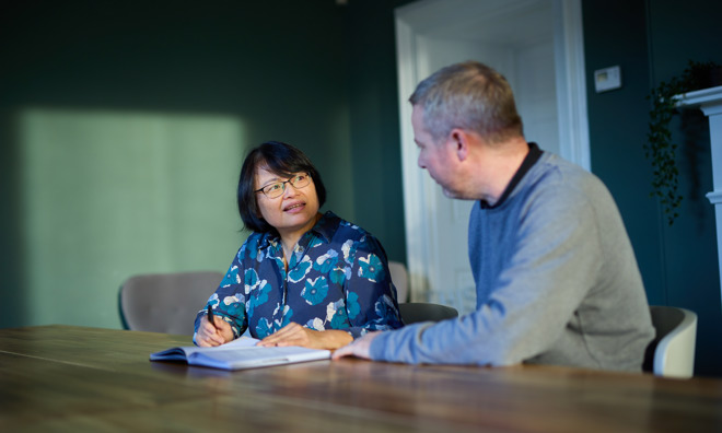 A man and woman sat a desk in discussion